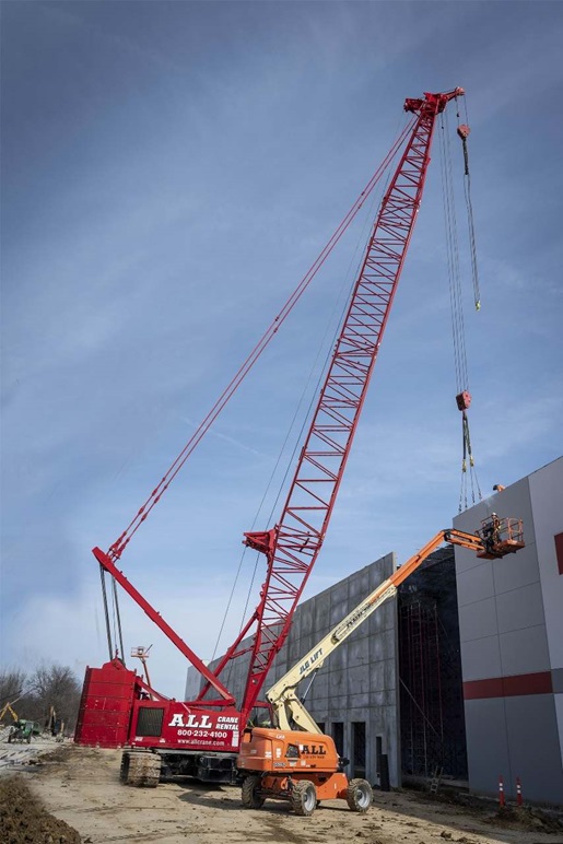 Red crawler crane and orange aerial lift on a jobsite
