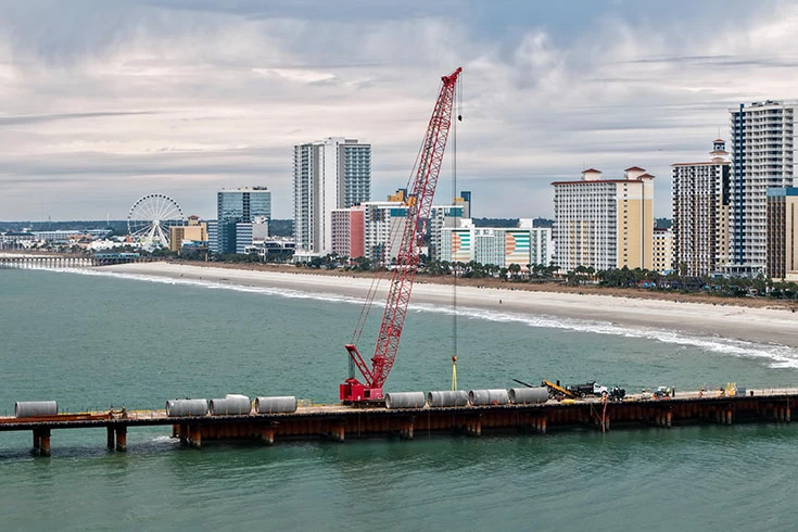 Crawler crane working on a dock on the ocean