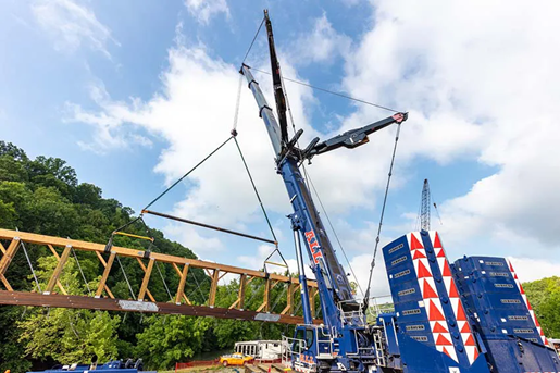 Blue all-terrain crane lifting a bridge