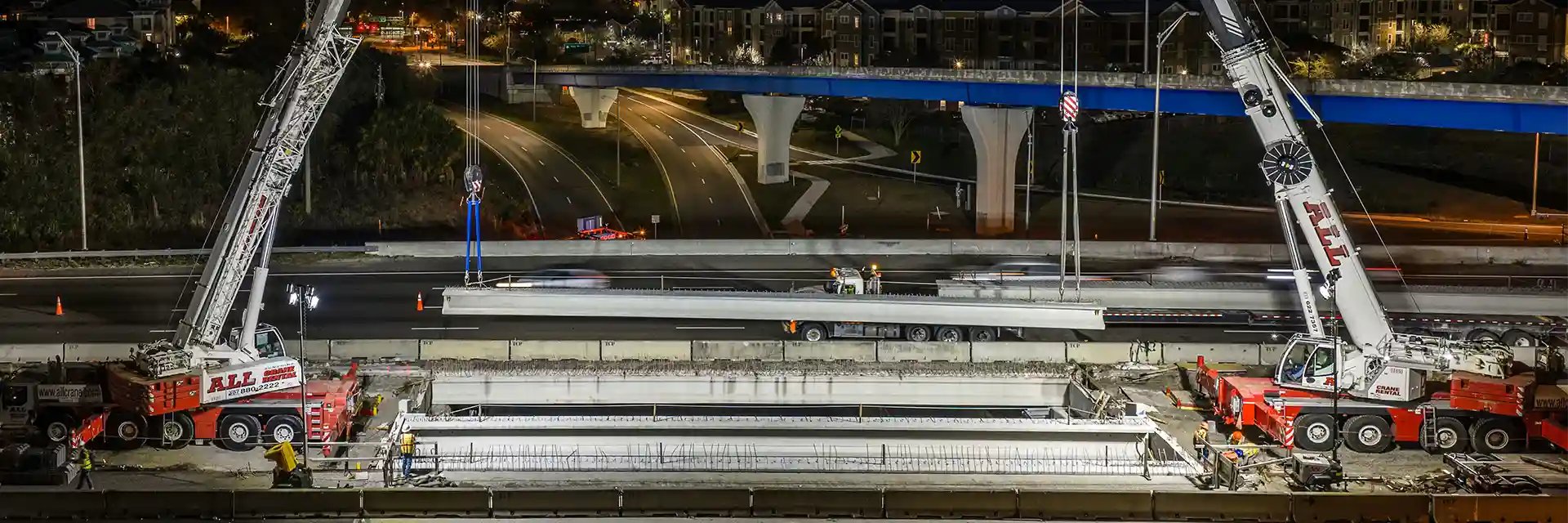 Two all-terrain cranes dual picking on a bridge