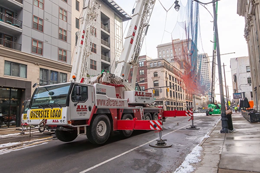 Two all-terrain cranes lifting art sculpture in Columbus