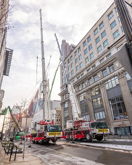 Two all-terrain cranes lifting the art sculpture in Columbus