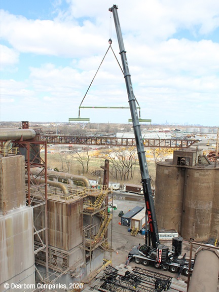 Two cranes pick and hold active plant’s conveyor bridge during demolition process