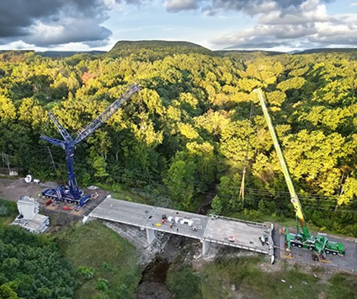 A blue Liebherr AT and a green Liebherr AT working on a bridge