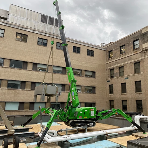 Green Maeda Mini Crane lifting AC unit on rooftop