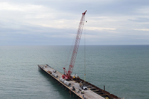 Crawler crane working on a dock on the ocean