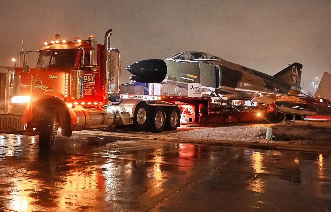 A crane hauling truck transporting a plane.